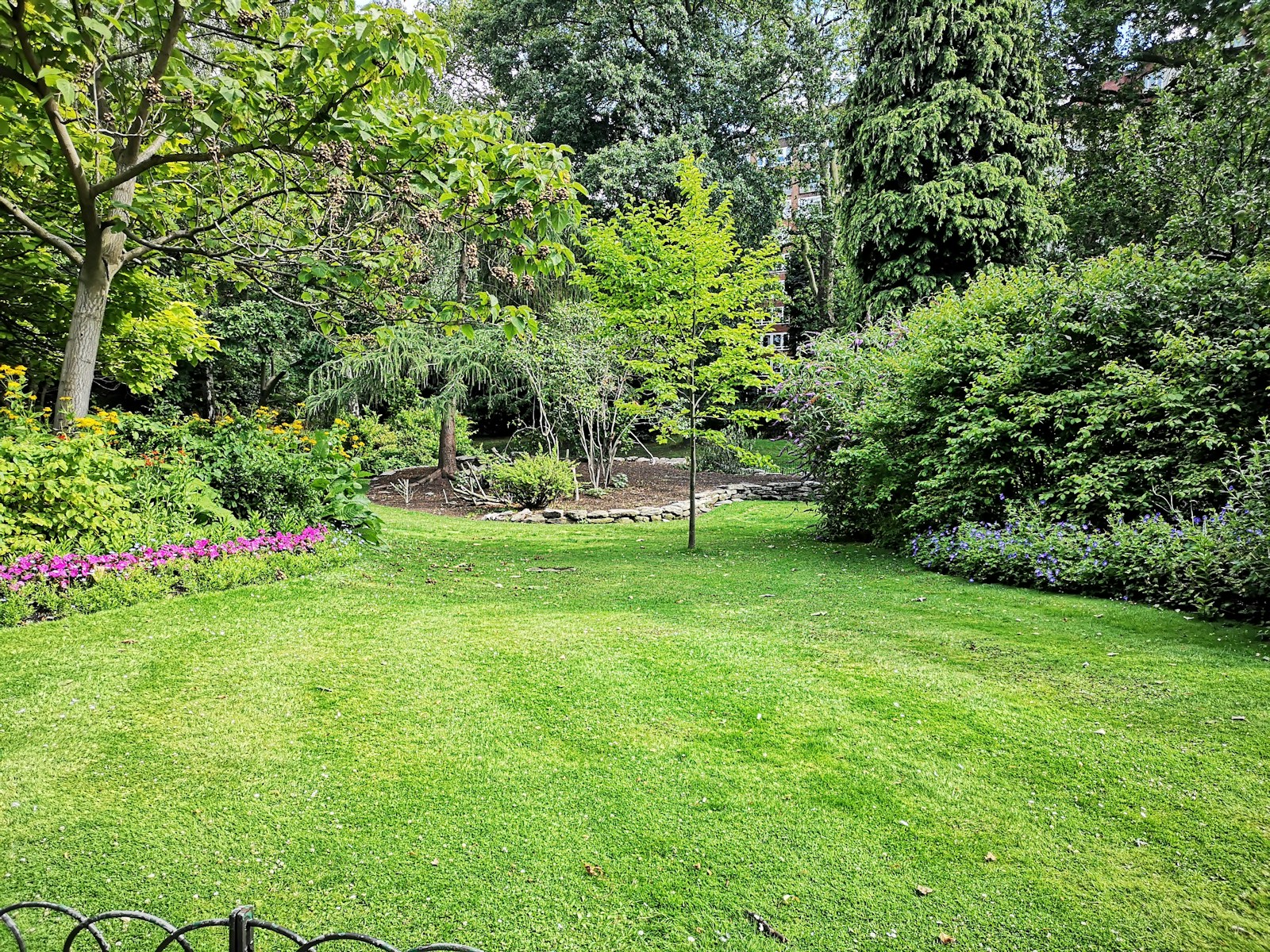Established perennial garden with stone path and box hedging