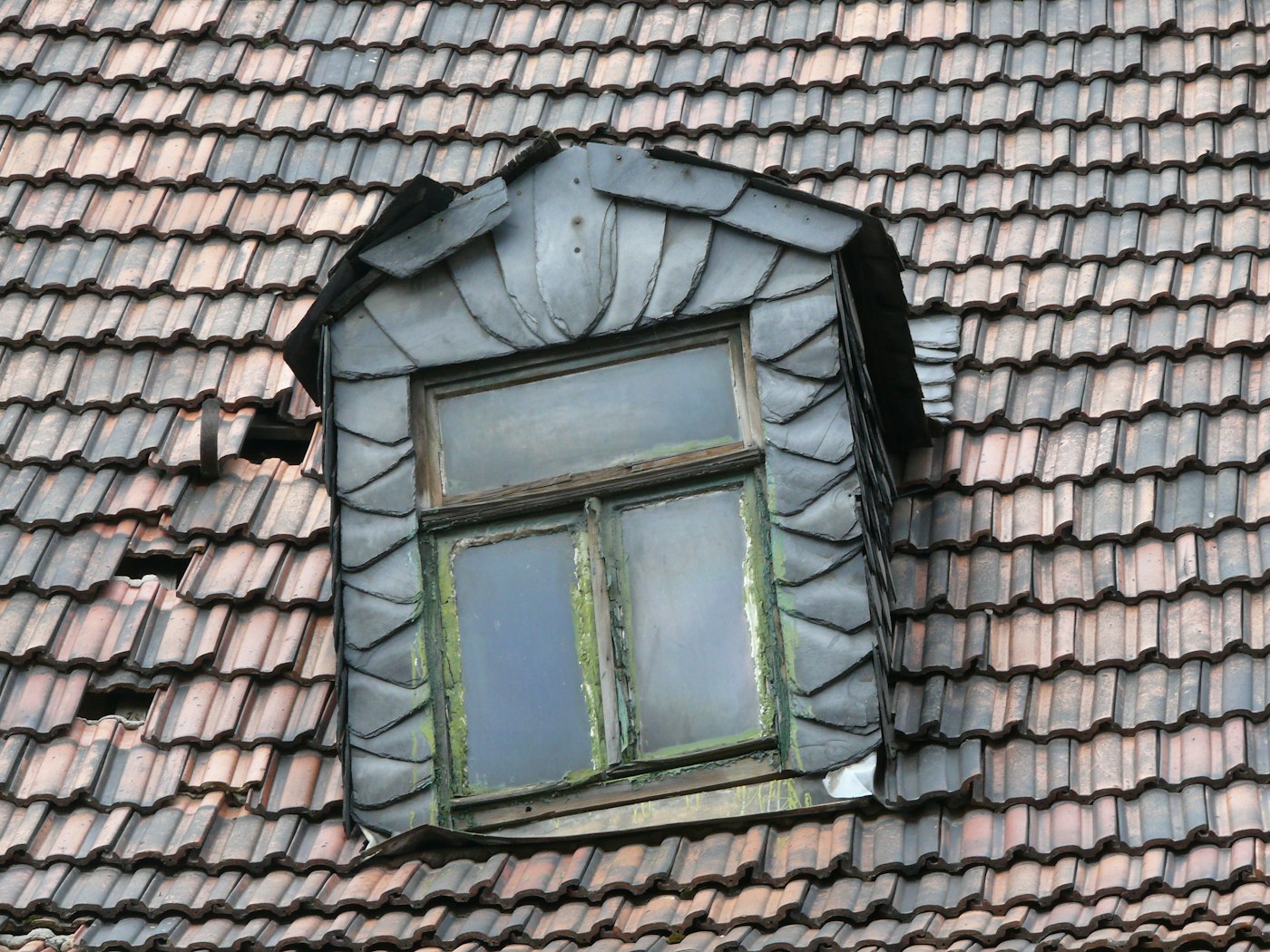 Slate-clad dormer window with intricate leadwork on a heritage Devon roof